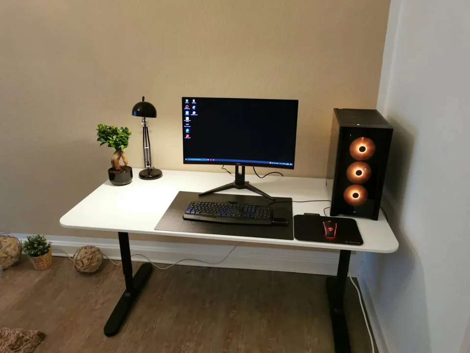 PC-Arbeitsplatz an einem weißen Schreibtisch mit Rechner, Bildschirm, Tastatur und Maus.