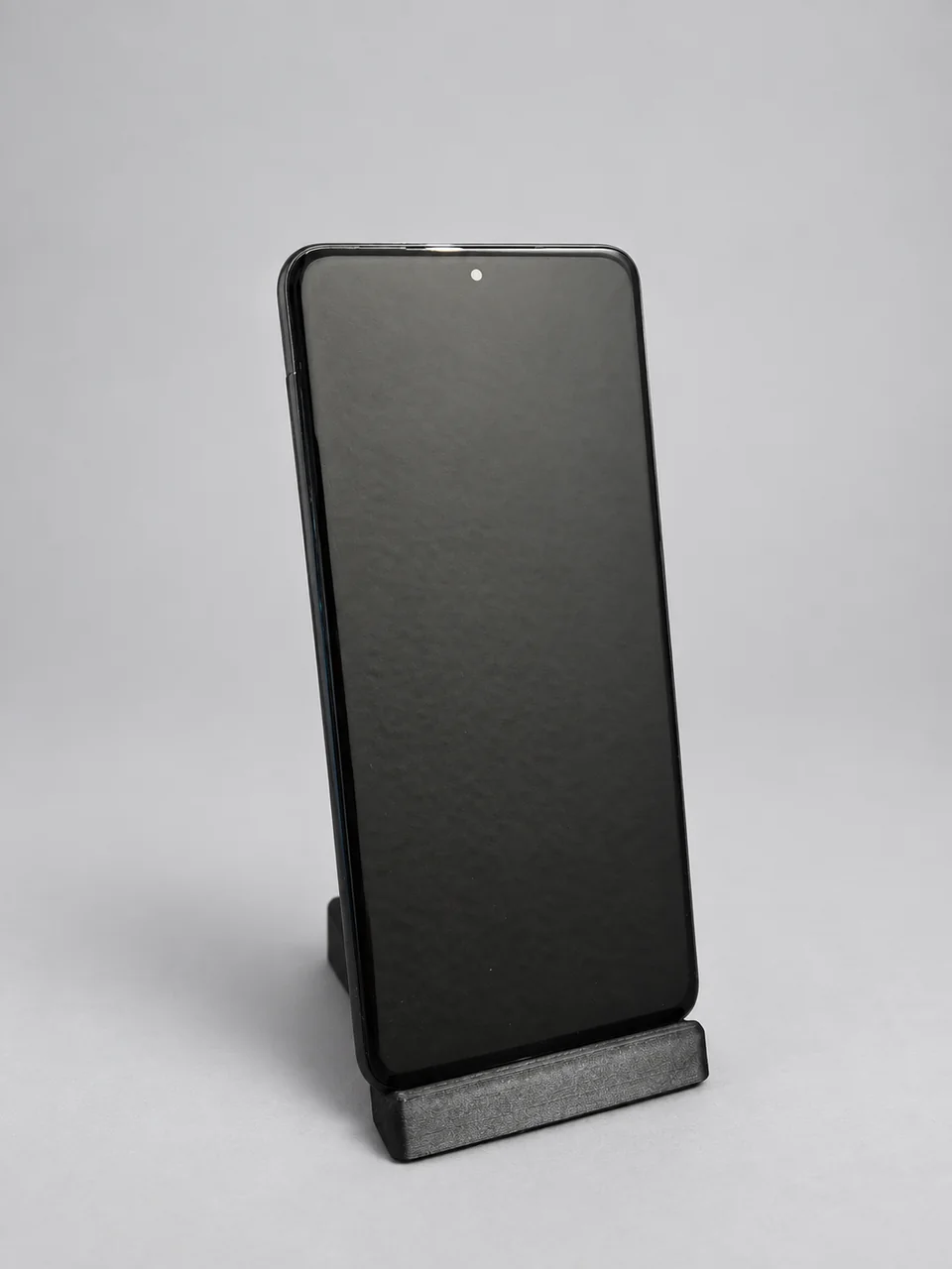 Aufbereitetes Galaxy S20 mit ausgeschaltetem Display auf einem kleinen Ständer.