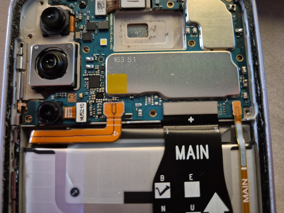 Nahaufnahme eines geöffneten Smartphones mit Kameramodulen, Platine und Verbindungskabeln.